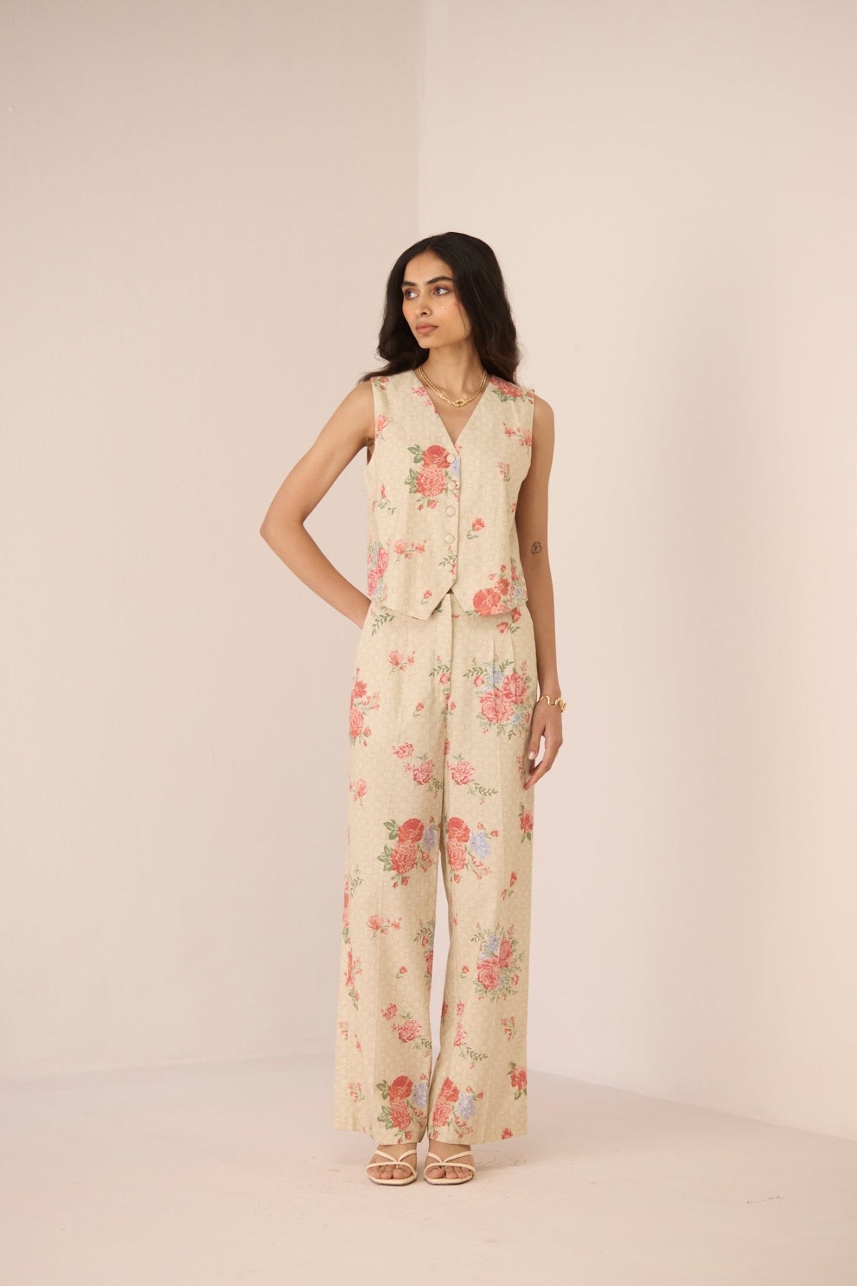 Woman wearing a floral jumpsuit on a plain background Calling June