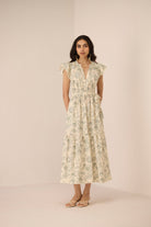 Woman wearing a floral dress against a plain background Calling June
