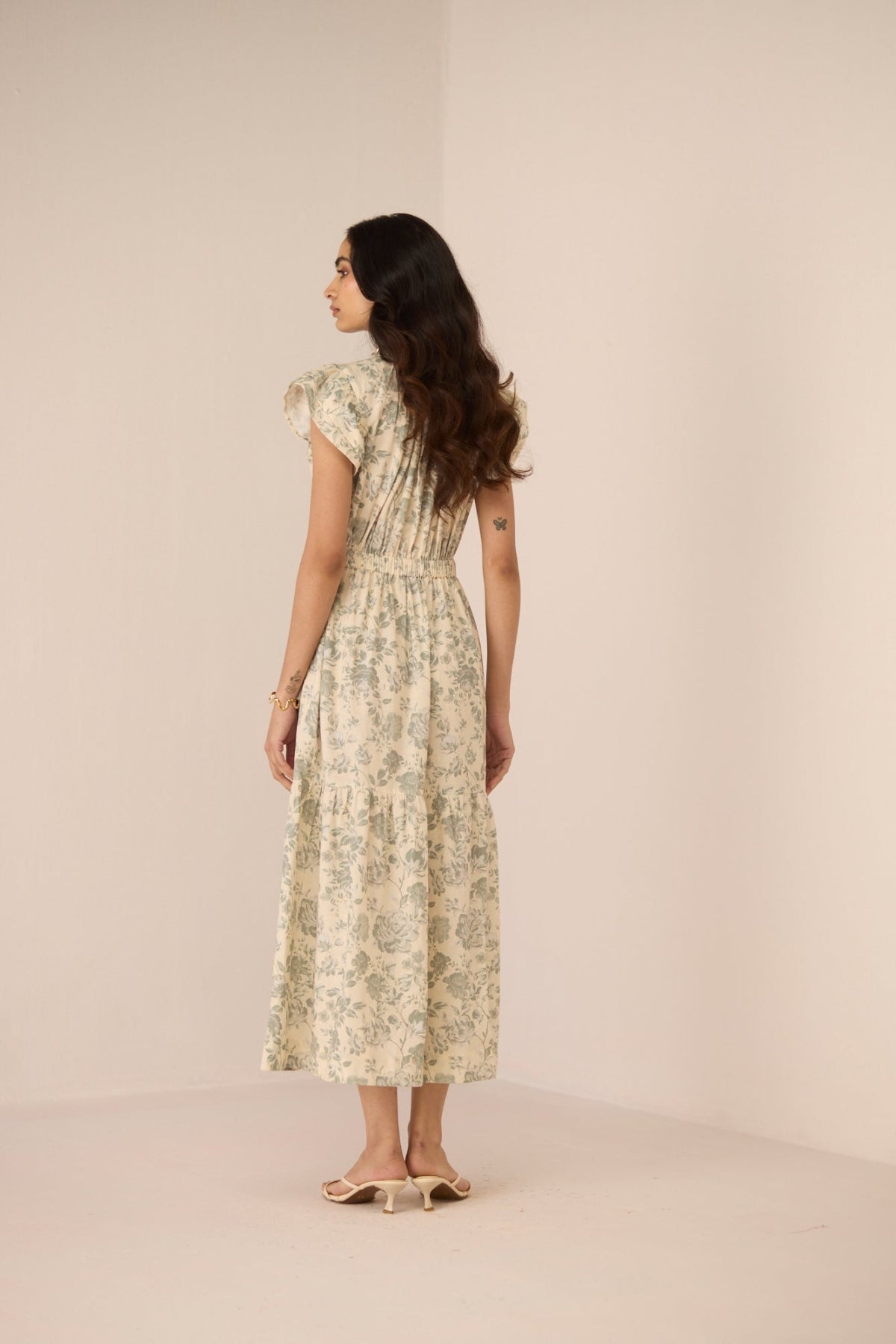 Woman wearing a floral dress against a plain background Calling June
