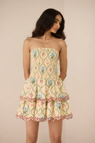 Woman wearing a floral strapless dress against a beige background Calling June