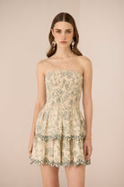 Woman wearing a strapless floral dress against a beige background Calling June