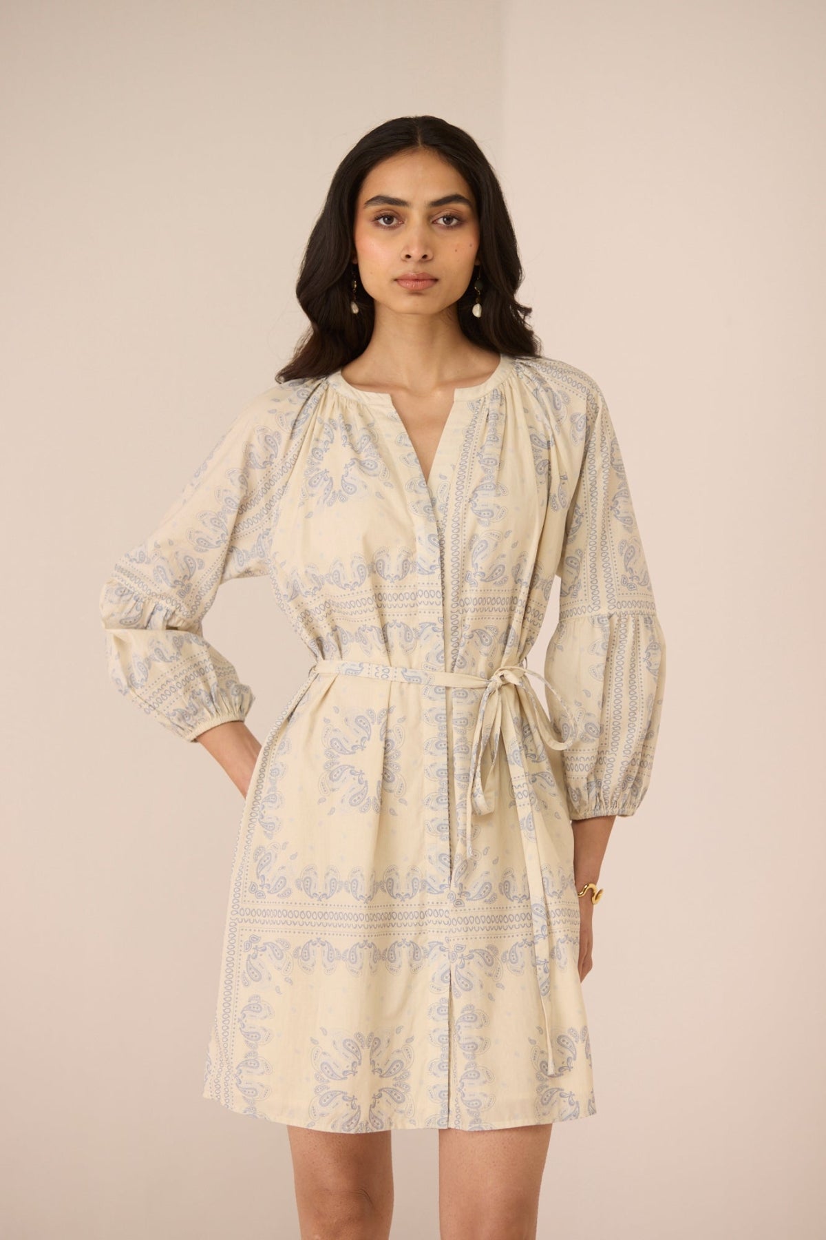 Woman wearing a beige patterned dress against a plain background Calling June