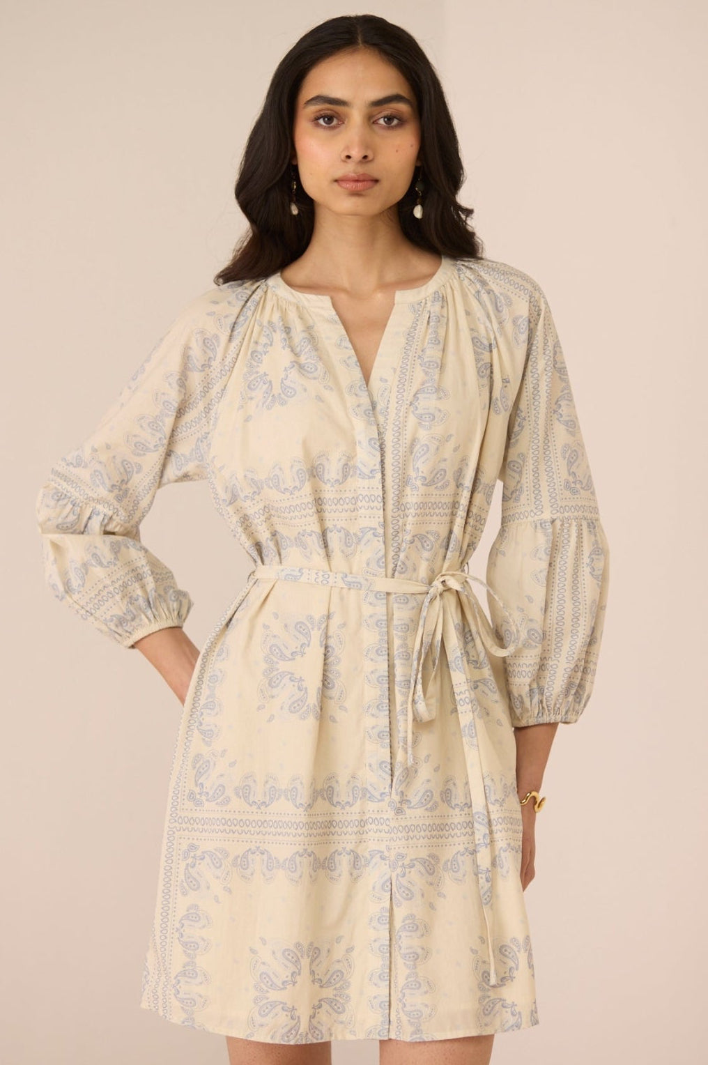 Woman wearing a beige patterned dress against a plain background Calling June