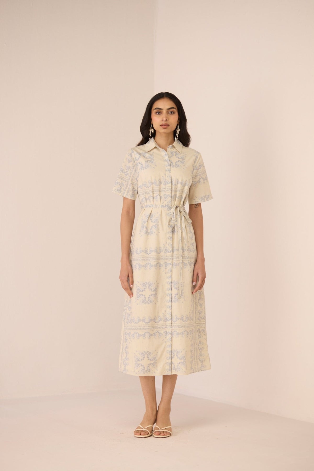 Woman wearing a light-colored dress with a subtle pattern on a plain background Calling June