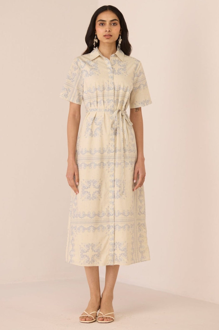 Woman wearing a light-colored dress with a subtle pattern on a plain background Calling June
