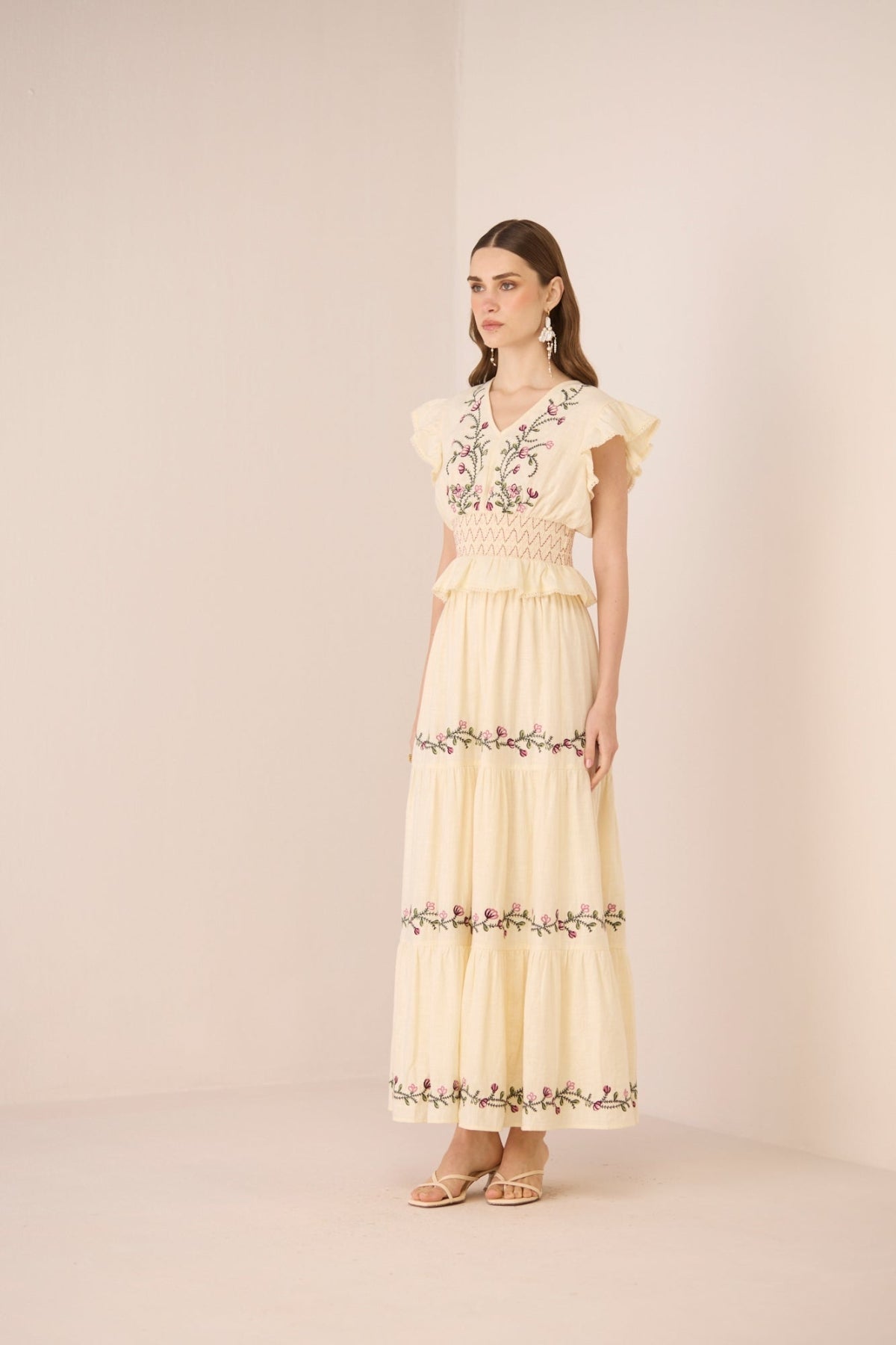 Woman wearing a light yellow set with floral embroidery on a beige background Calling June