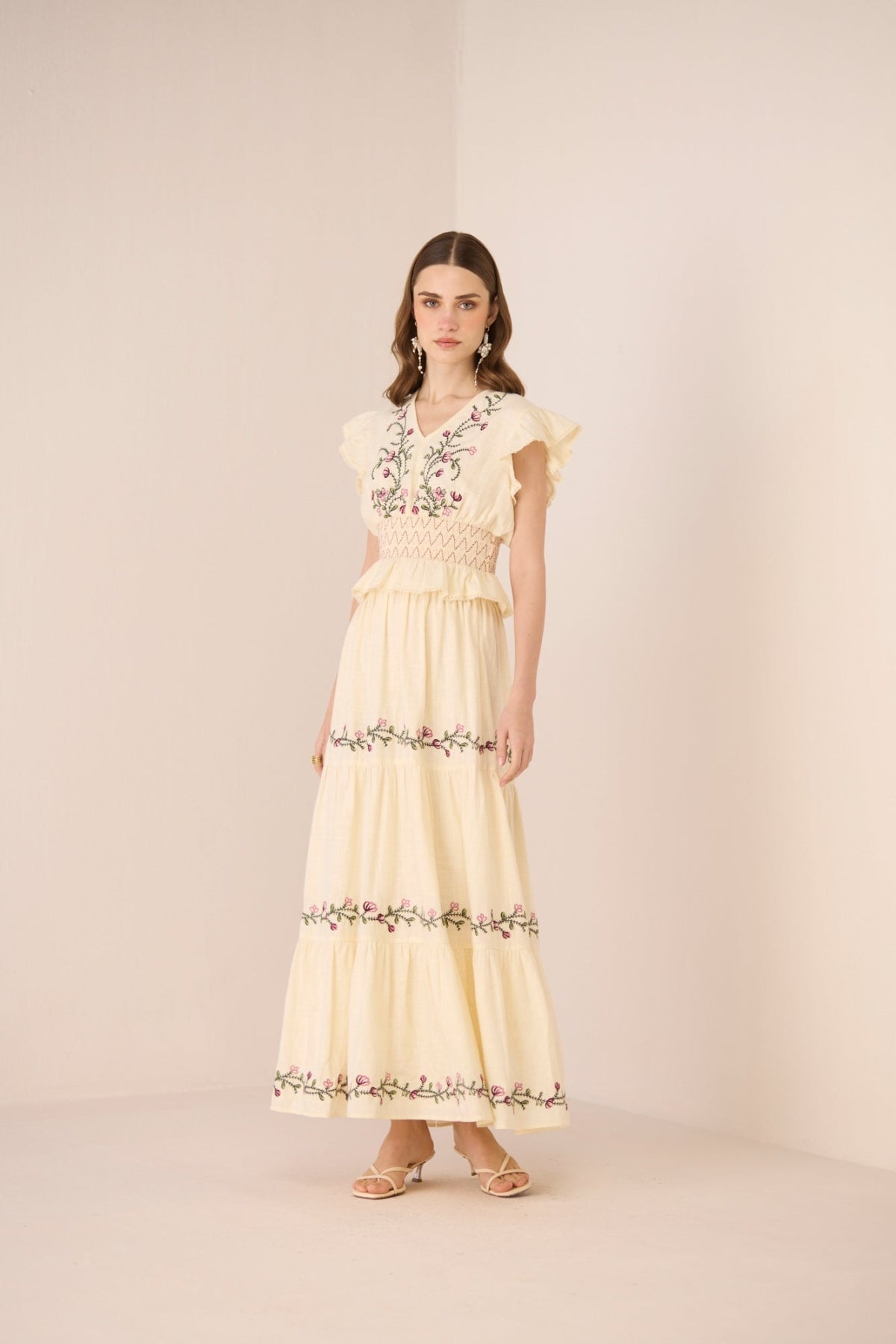 Woman wearing a light yellow set with floral embroidery on a beige background Calling June