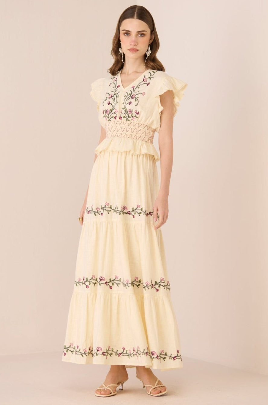 Woman wearing a light yellow set with floral embroidery on a beige background Calling June