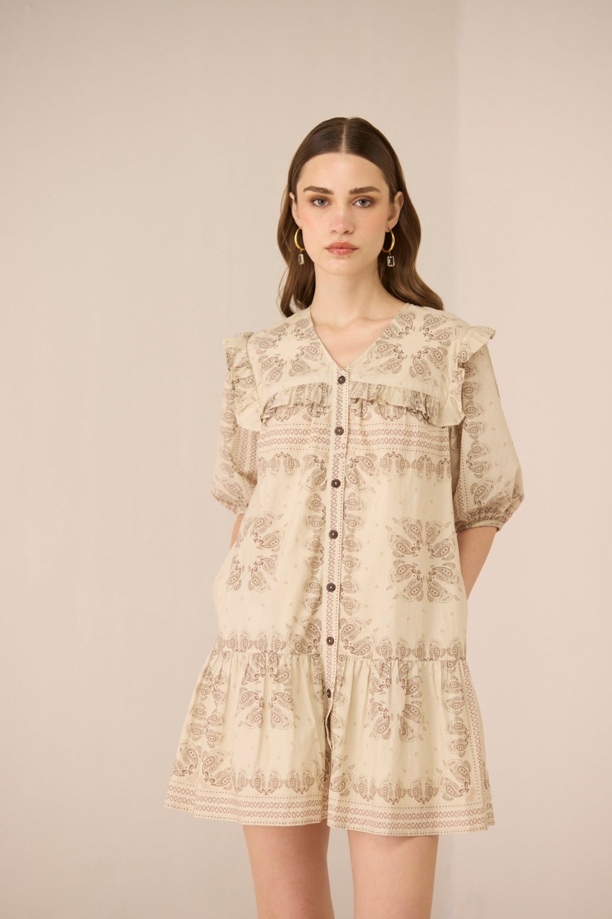 Woman wearing a beige floral dress against a plain background Calling June