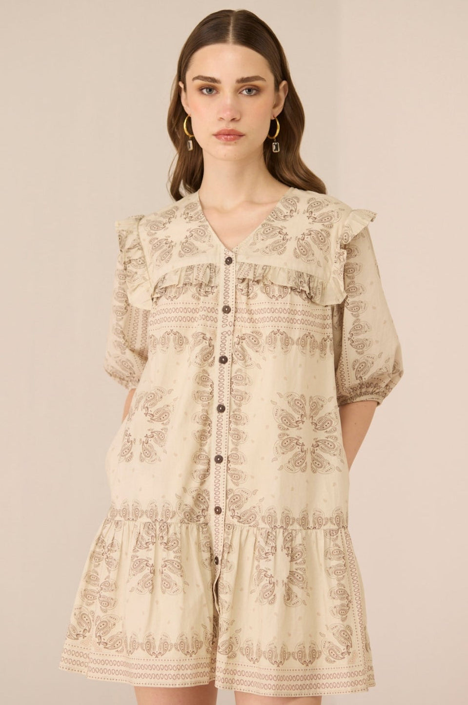 Woman wearing a beige floral dress against a plain background Calling June