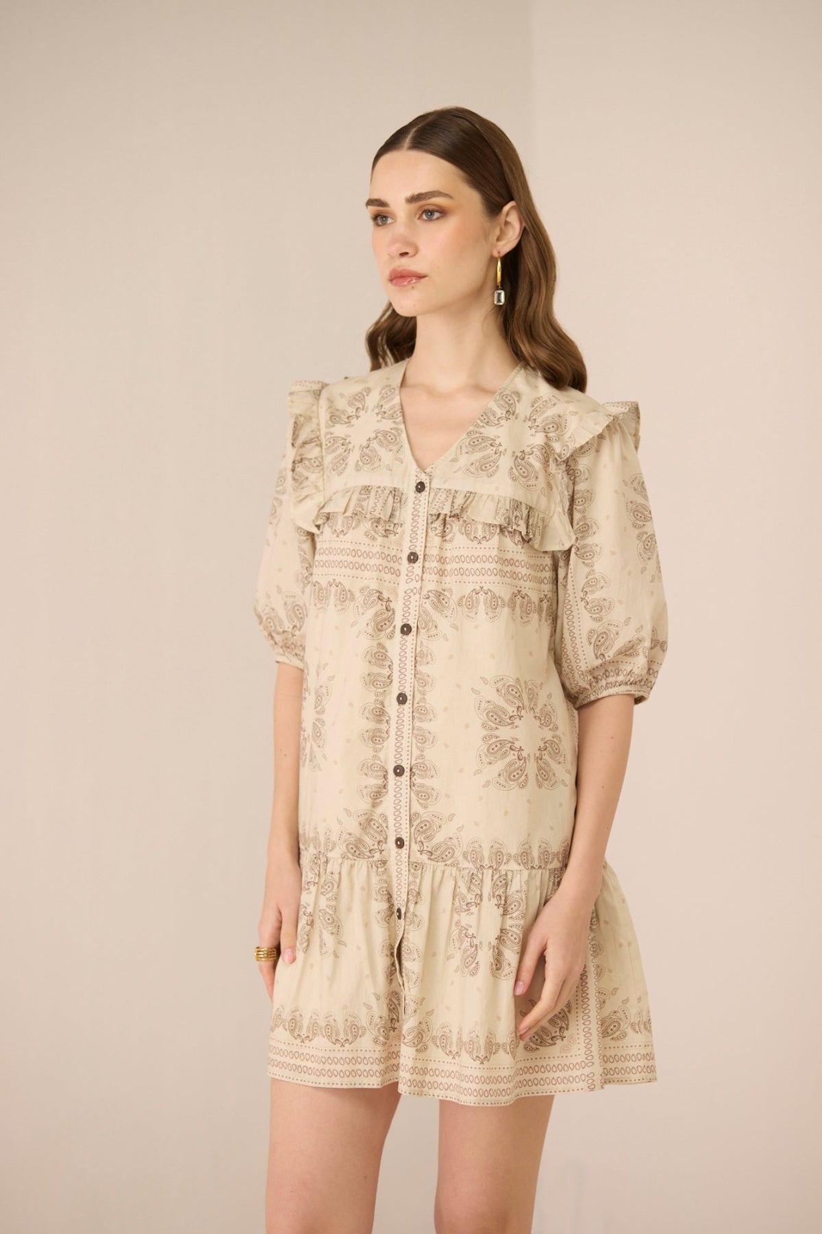 Woman wearing a beige floral dress against a plain background Calling June