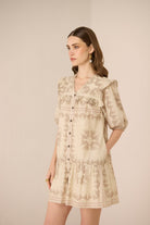 Woman wearing a beige floral dress against a plain background Calling June