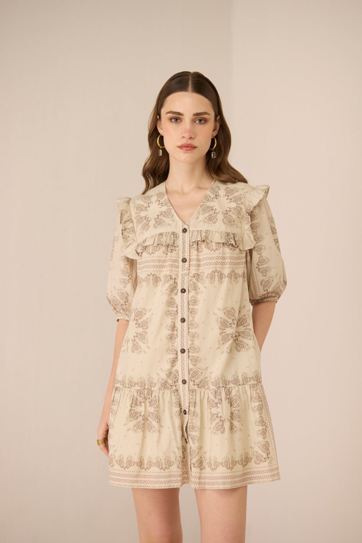 Woman wearing a beige floral dress against a plain background Calling June