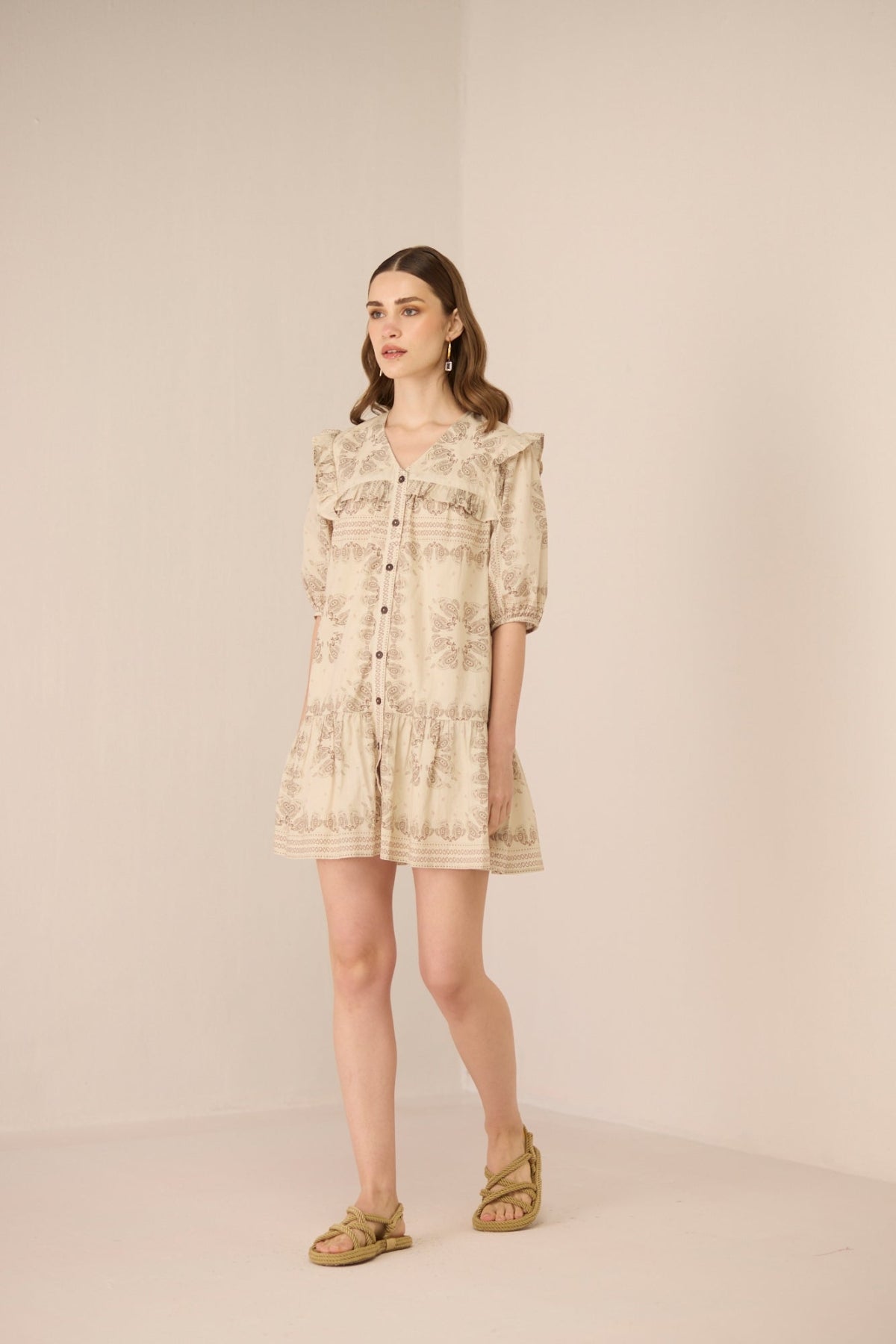 Woman wearing a beige floral dress against a plain background Calling June