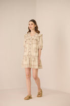 Woman wearing a beige floral dress against a plain background Calling June