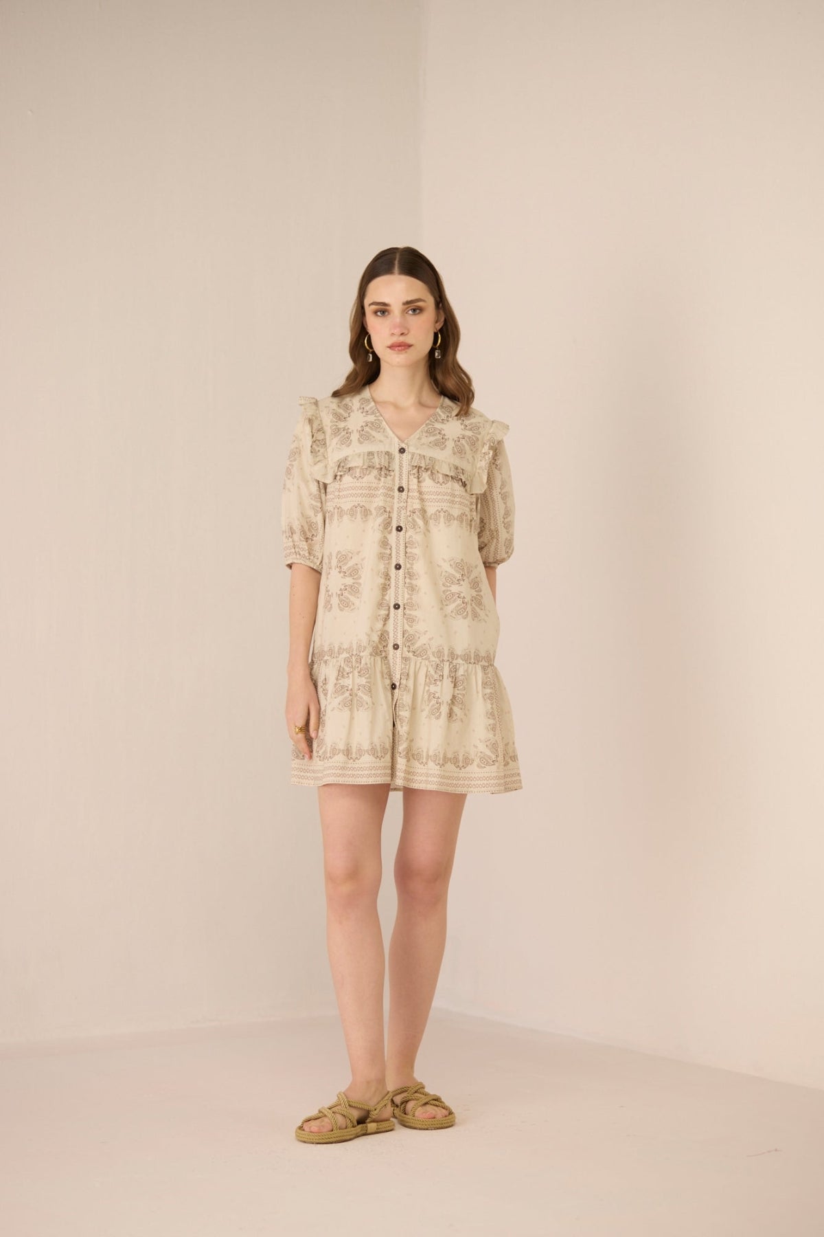 Woman wearing a beige floral dress against a plain background Calling June