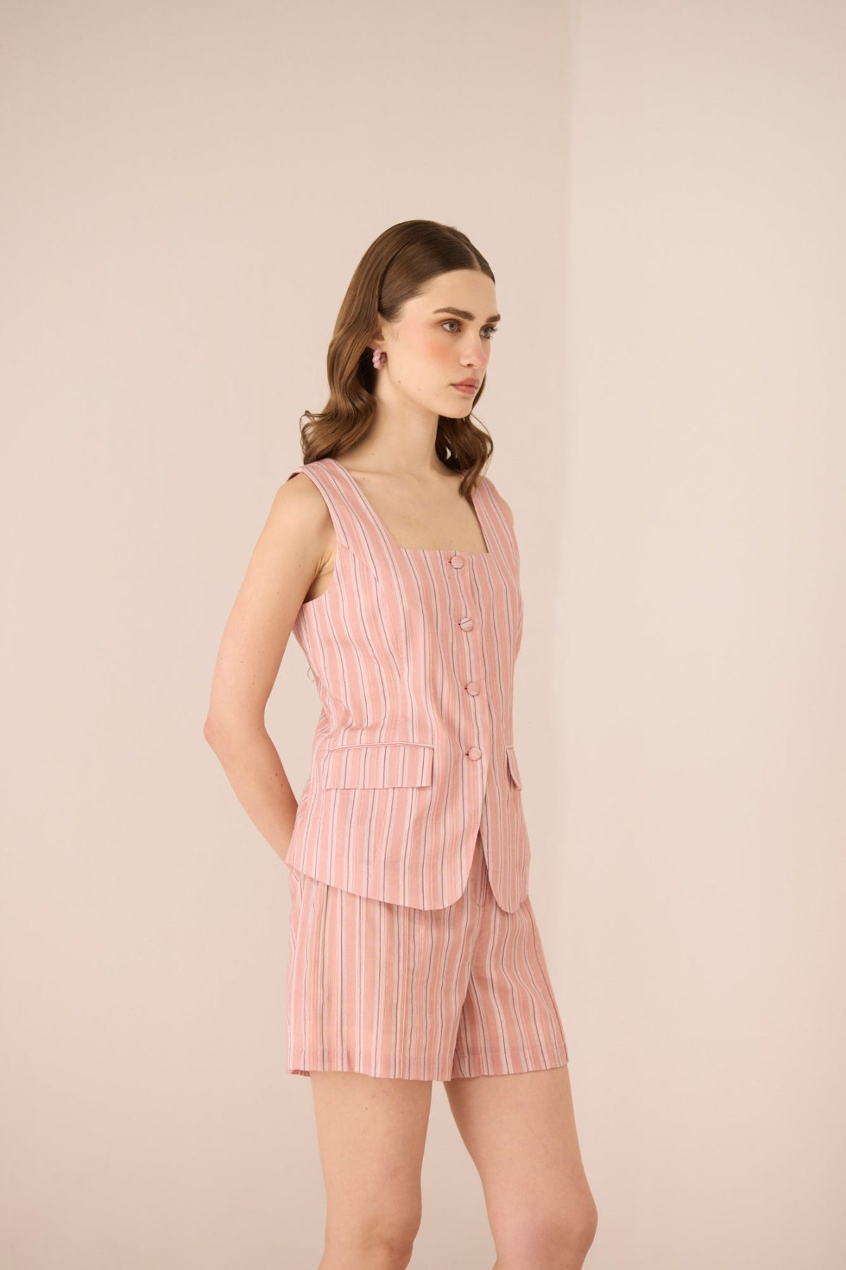 Woman wearing a pink striped outfit on a beige background Calling June
