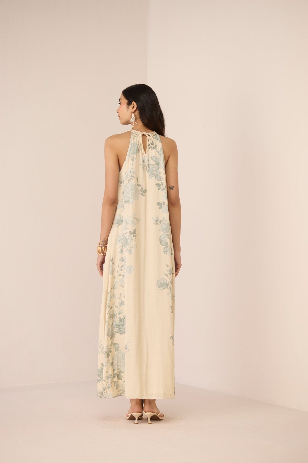 Woman wearing a floral halter neck dress against a plain background Calling June