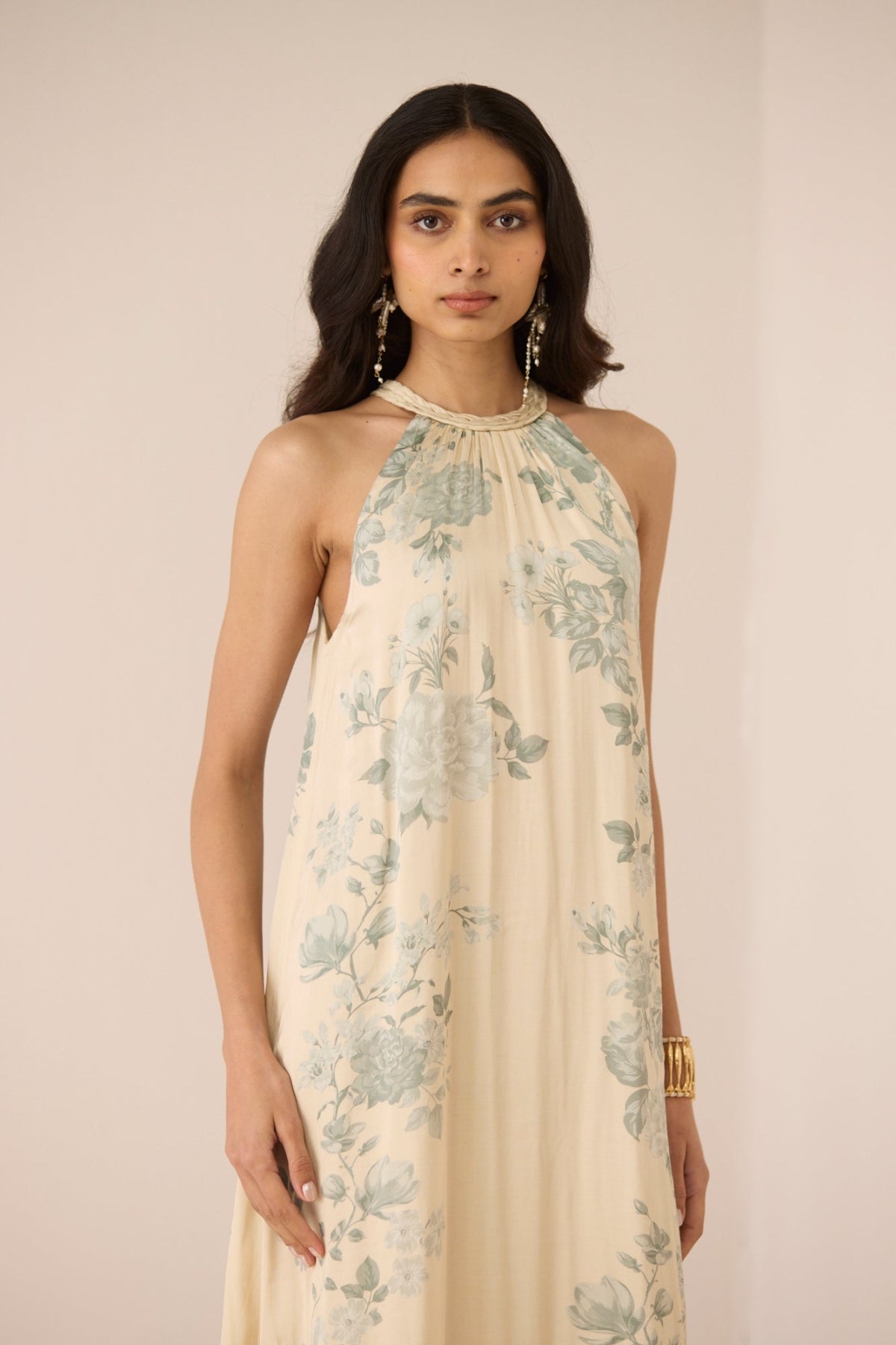 Woman wearing a floral halter neck dress against a plain background Calling June