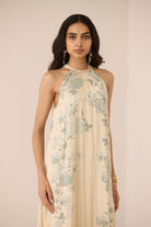 Woman wearing a floral halter neck dress against a plain background Calling June