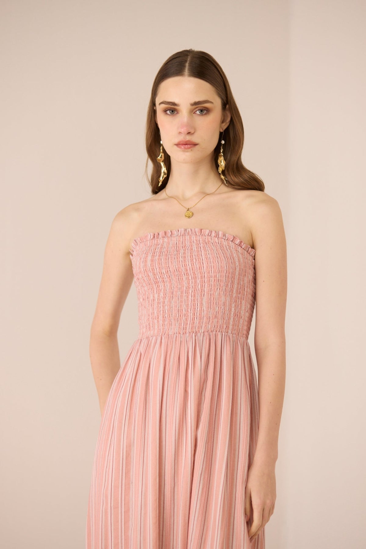 Woman wearing a pink strapless dress against a beige background Calling June