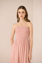 Woman wearing a pink strapless dress against a beige background Calling June