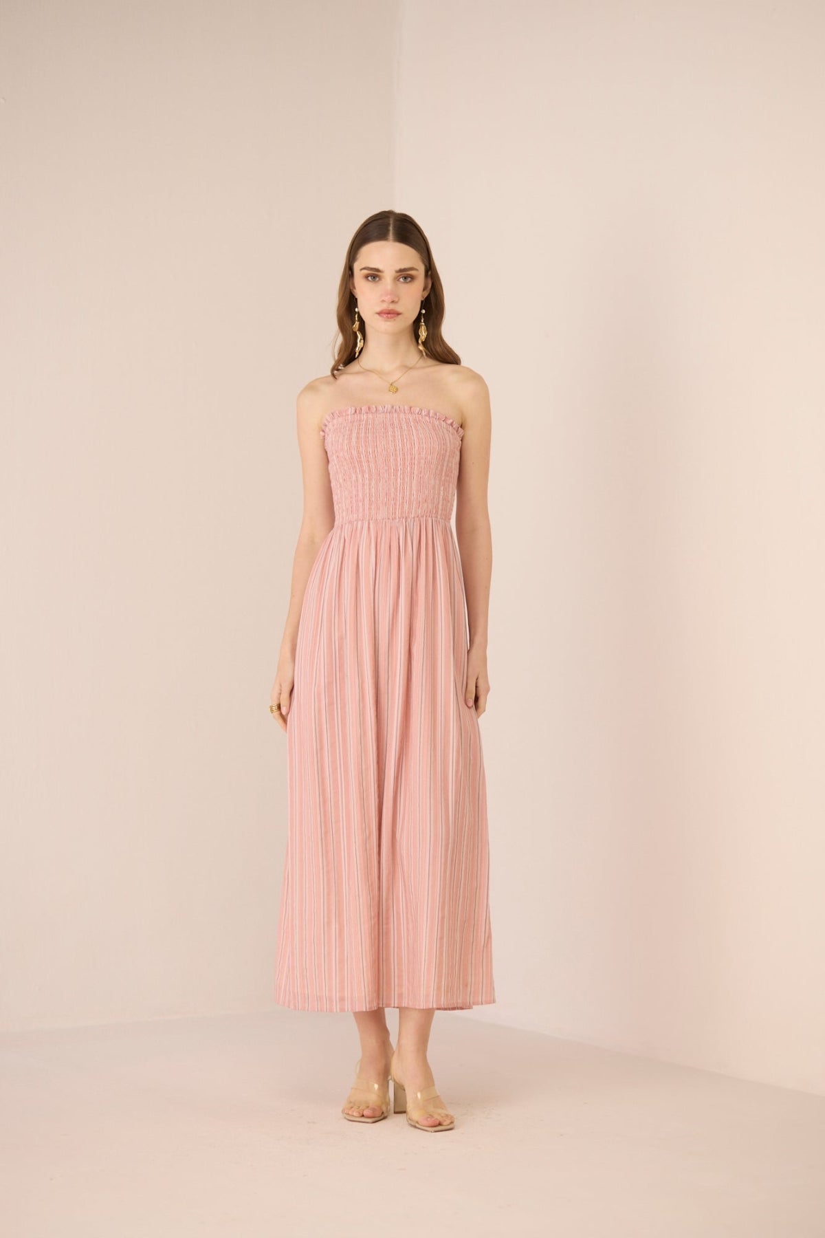 Woman wearing a pink strapless dress against a plain background Calling June