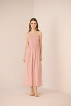 Woman wearing a pink strapless dress against a plain background Calling June