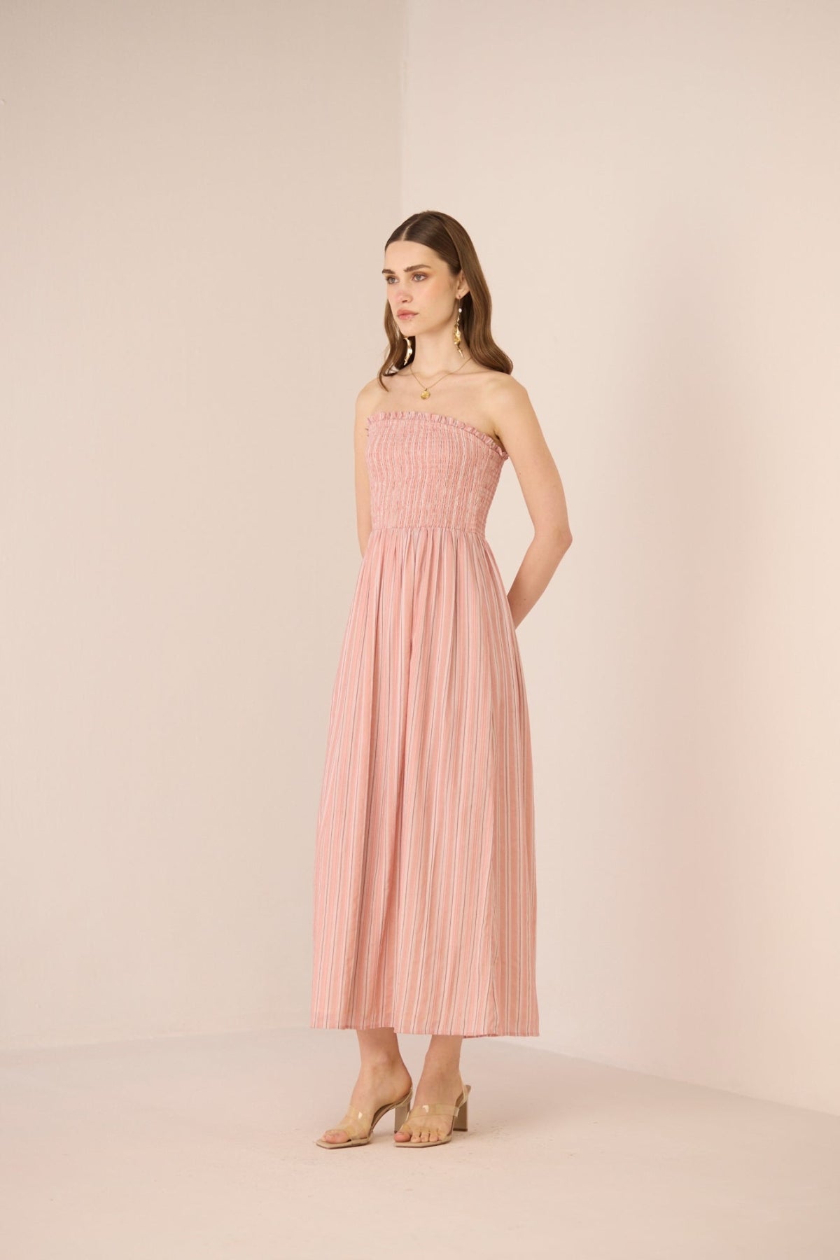 Woman wearing a strapless pink dress against a beige background Calling June