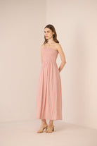 Woman wearing a strapless pink dress against a beige background Calling June