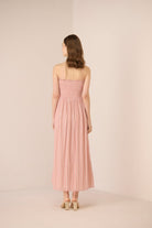 Woman wearing a pink strapless dress against a plain background Calling June