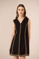 Black dress with gold trim worn by a model on a beige background Calling June