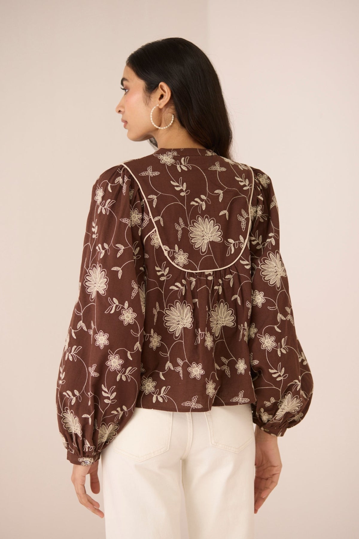 Woman wearing a brown floral blouse against a beige background Calling June