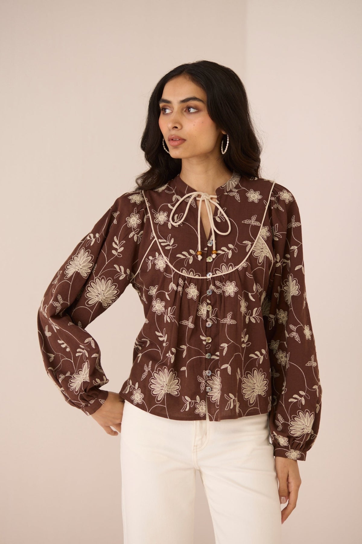 Woman wearing a brown floral blouse with a beige background Calling June