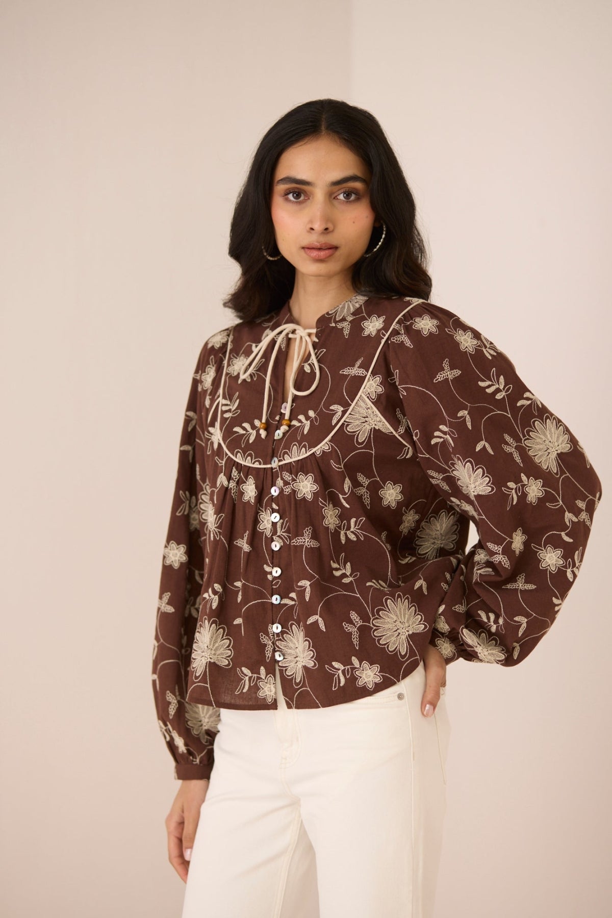 Woman wearing a brown floral blouse against a plain background Calling June