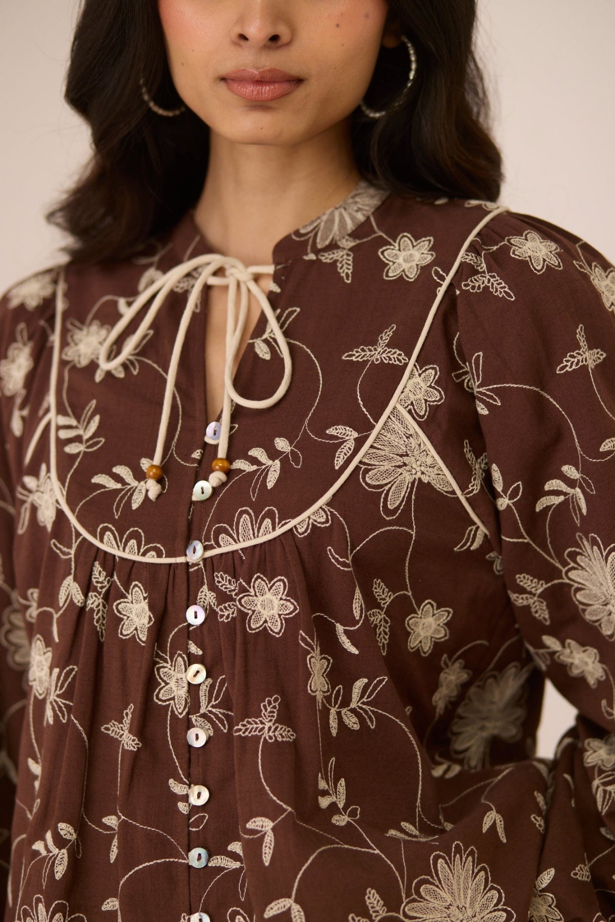 Woman wearing a brown floral dress with a close-up of the neckline Calling June