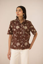 Woman wearing a brown floral blouse against a beige background Calling June