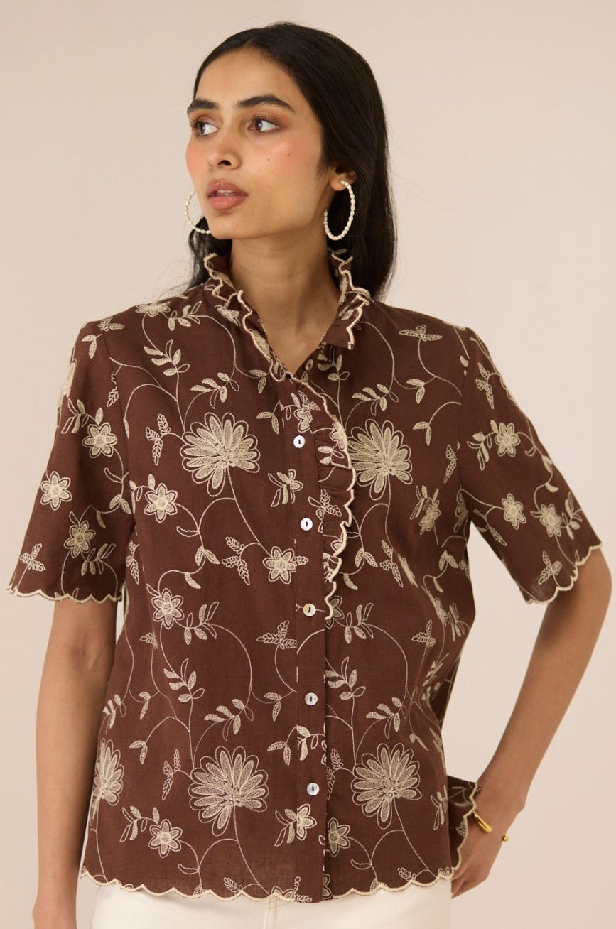 Woman wearing a brown floral blouse against a beige background Calling June
