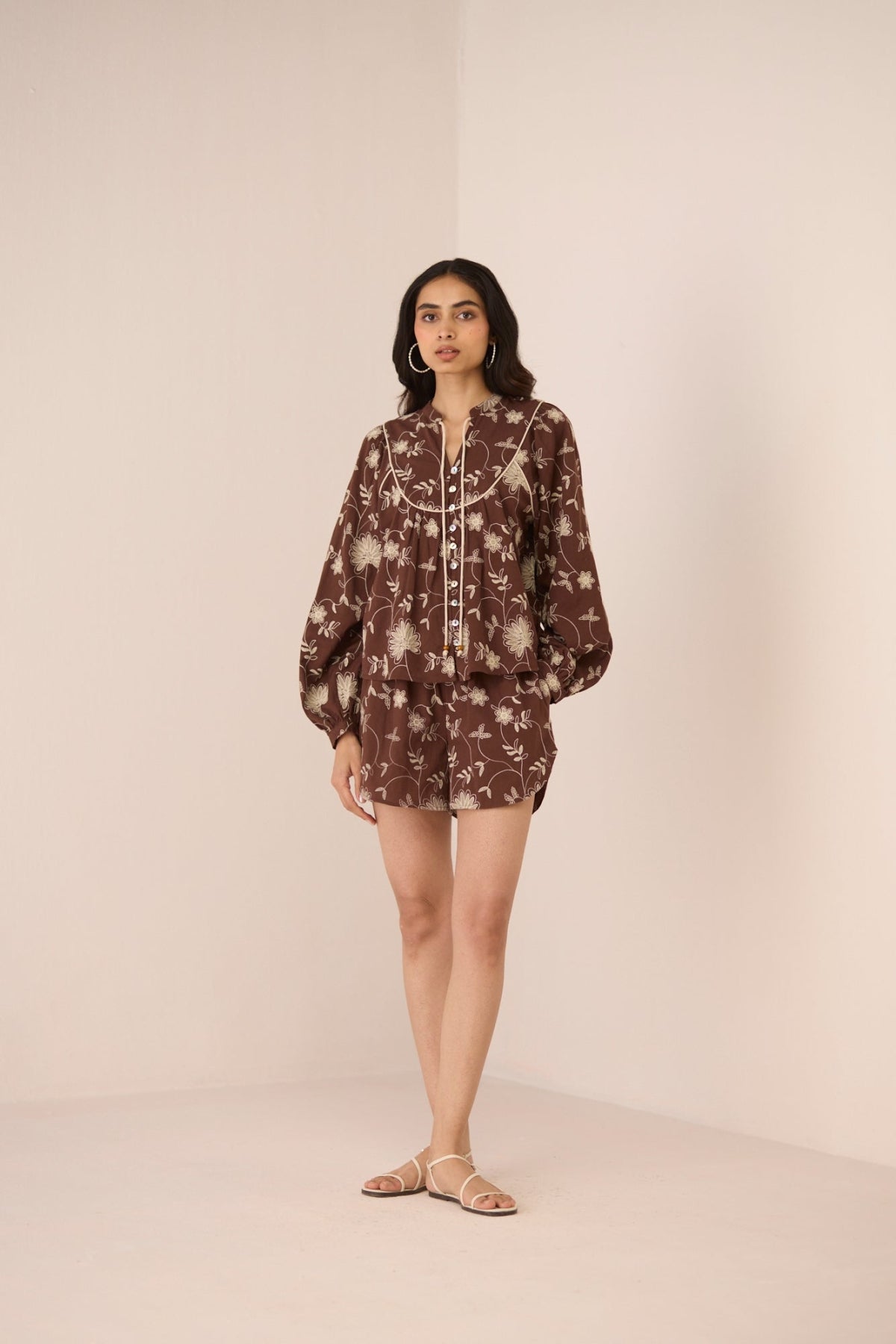 Woman wearing a brown floral dress against a beige background Calling June