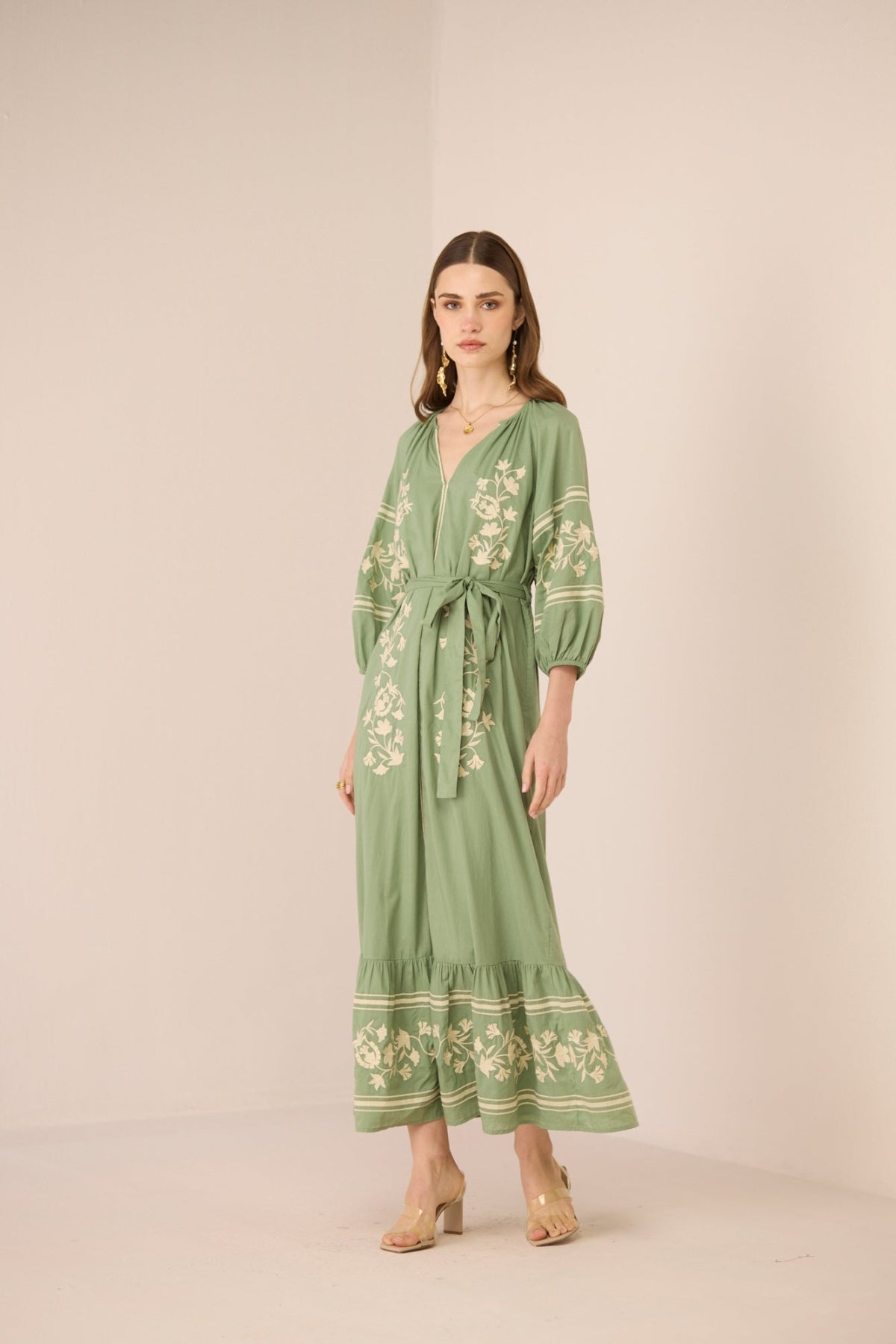 Woman wearing a green embroidered dress on a beige background Calling June