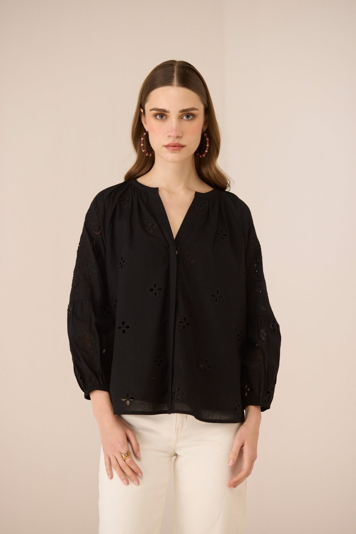 Woman wearing a black blouse with floral details on a beige background Calling June