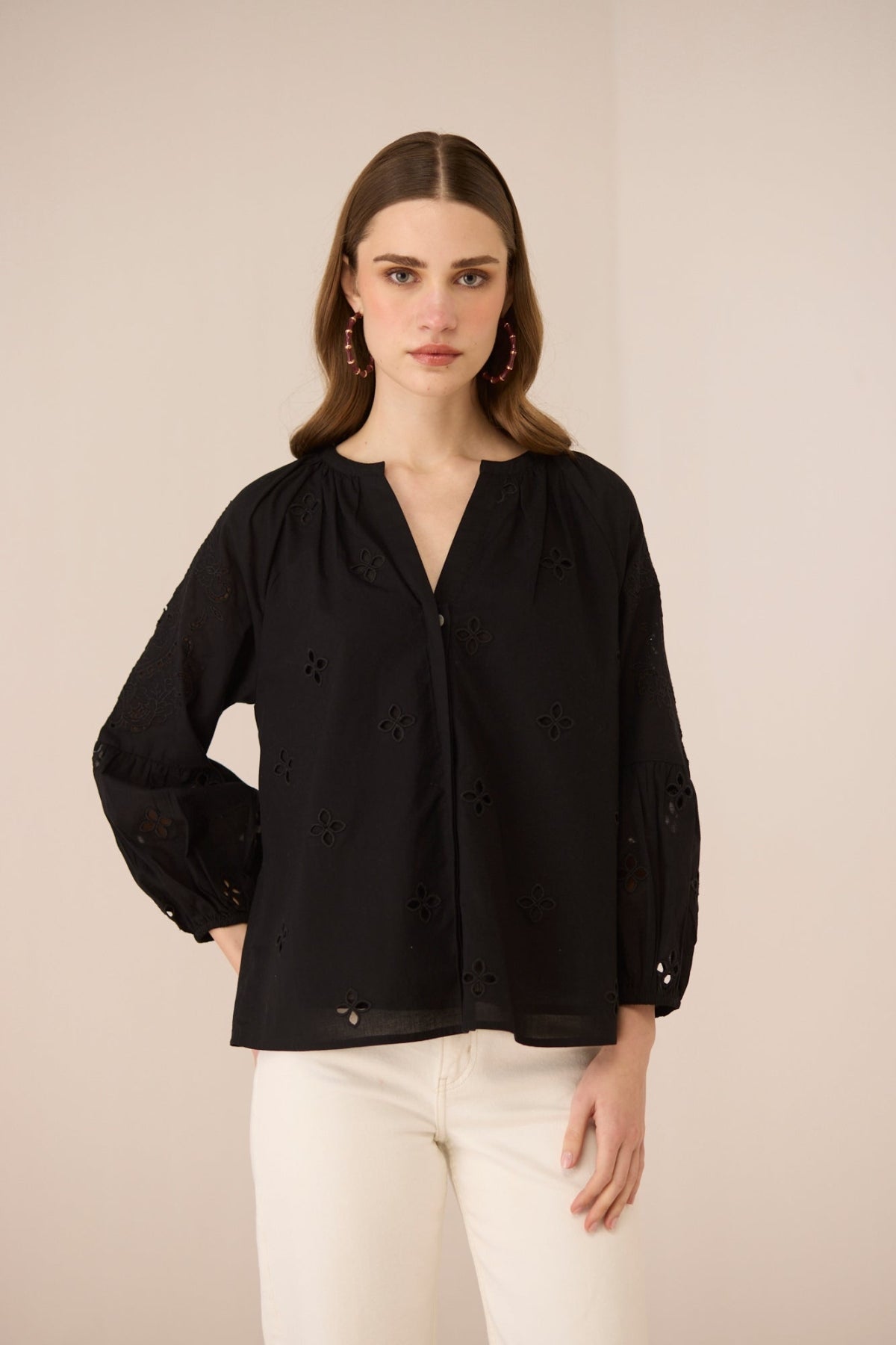 Woman wearing a black blouse with white pants on a beige background Calling June