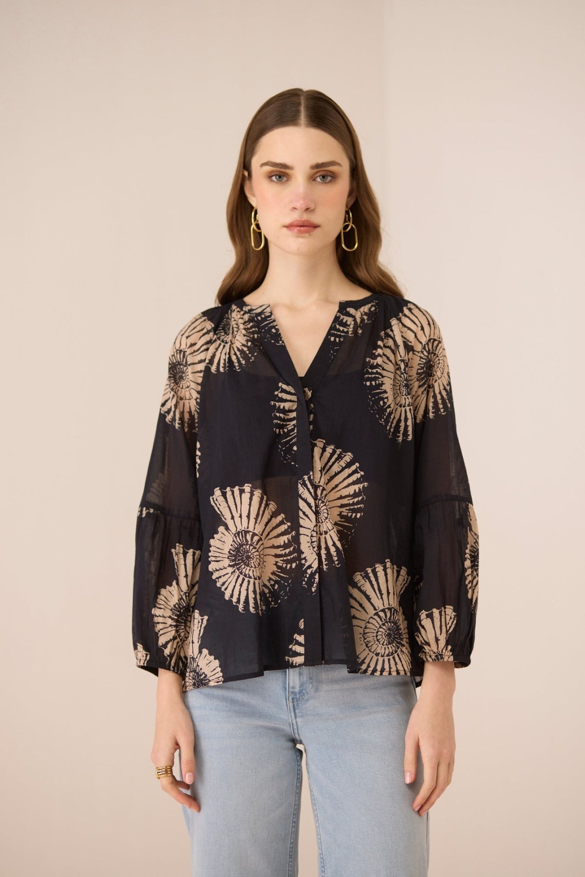 Woman wearing a black blouse with gold floral patterns on a beige background Calling June