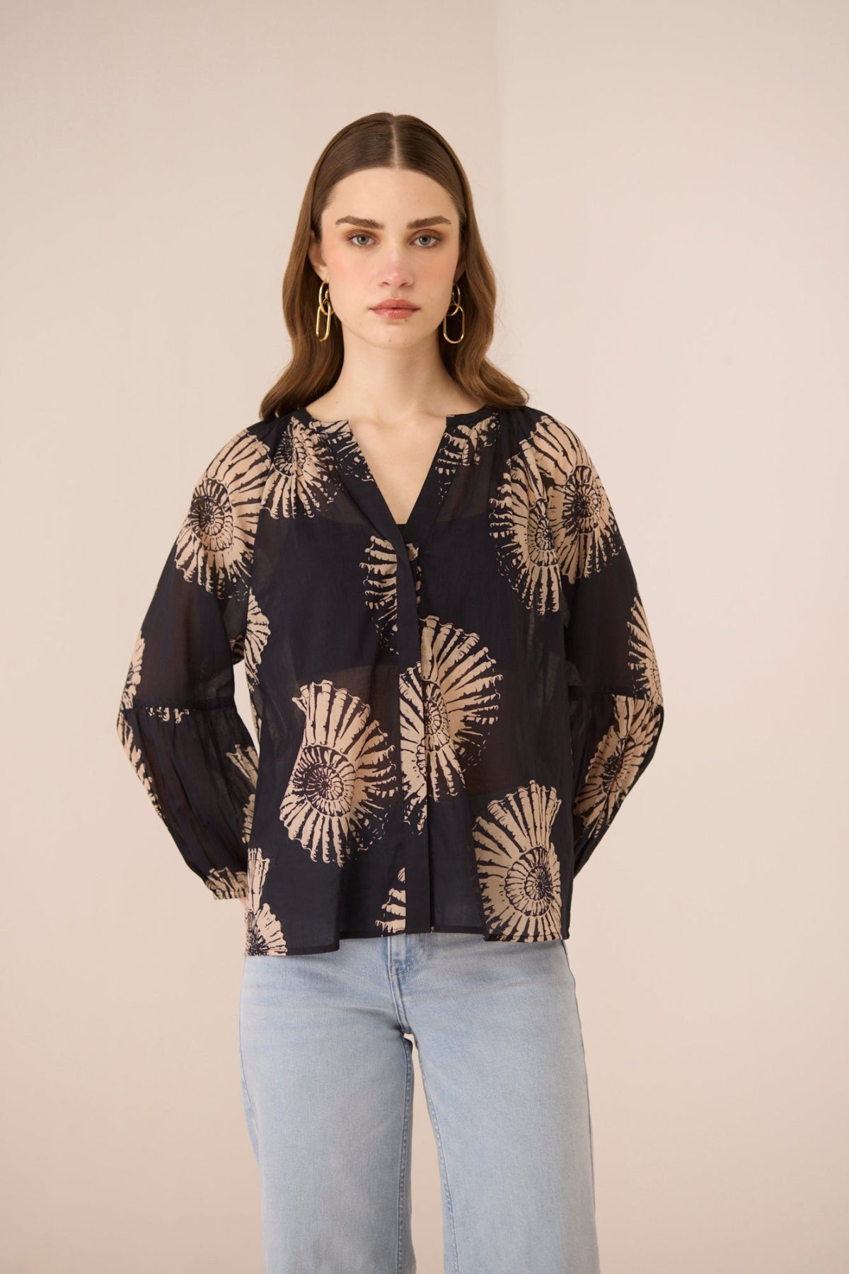 Woman wearing a black blouse with beige floral patterns on a beige background Calling June