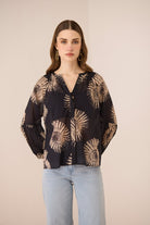 Woman wearing a black blouse with beige floral patterns on a beige background Calling June