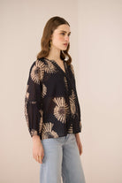 Woman wearing a black blouse with beige floral patterns on a beige background Calling June