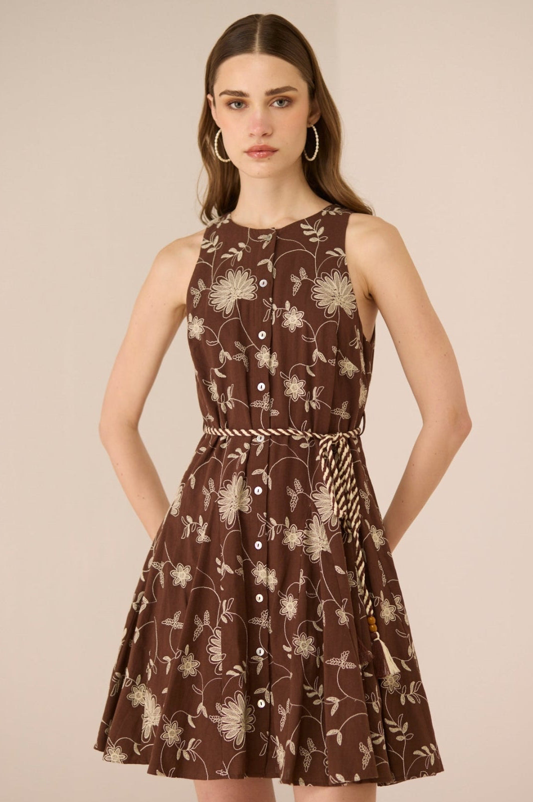Woman wearing a brown floral dress against a beige background Calling June