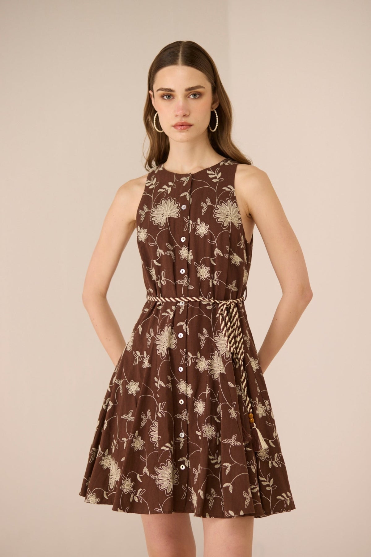 Woman wearing a brown floral dress against a beige background Calling June