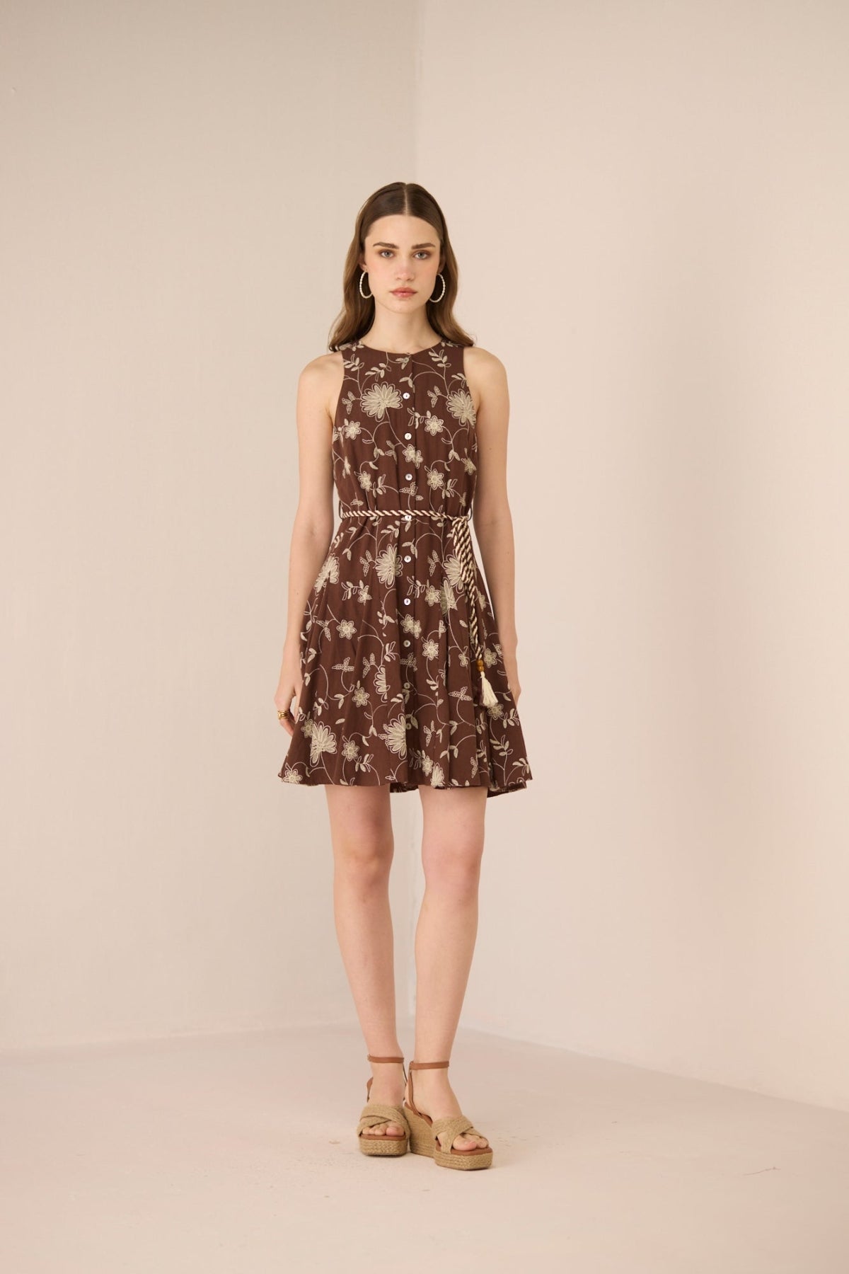 Woman wearing a brown floral dress against a beige background Calling June