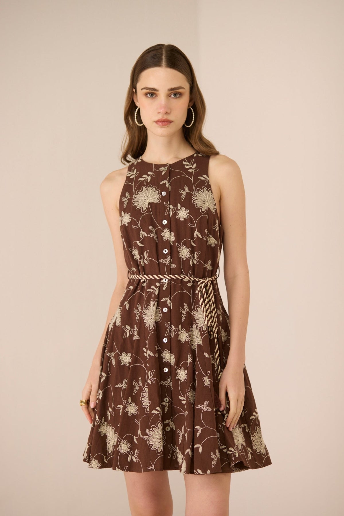 Woman wearing a brown floral dress against a beige background Calling June